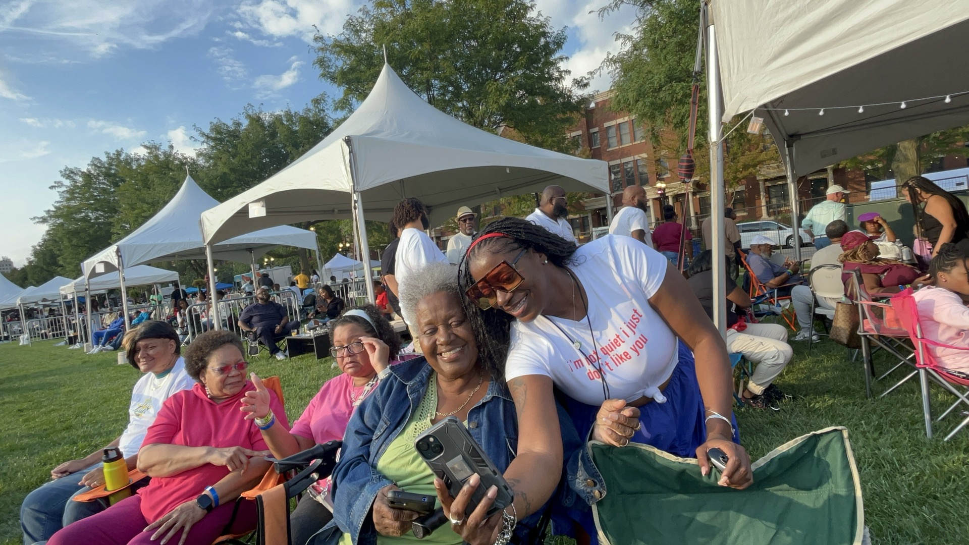 Fans smiling on the lawn with tents in the background